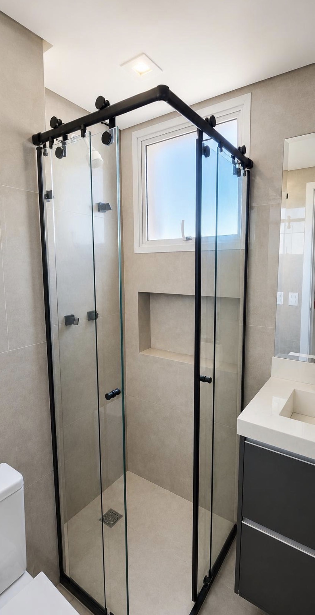 Banheiro reformado com box de vidro e acabamento contemporâneo